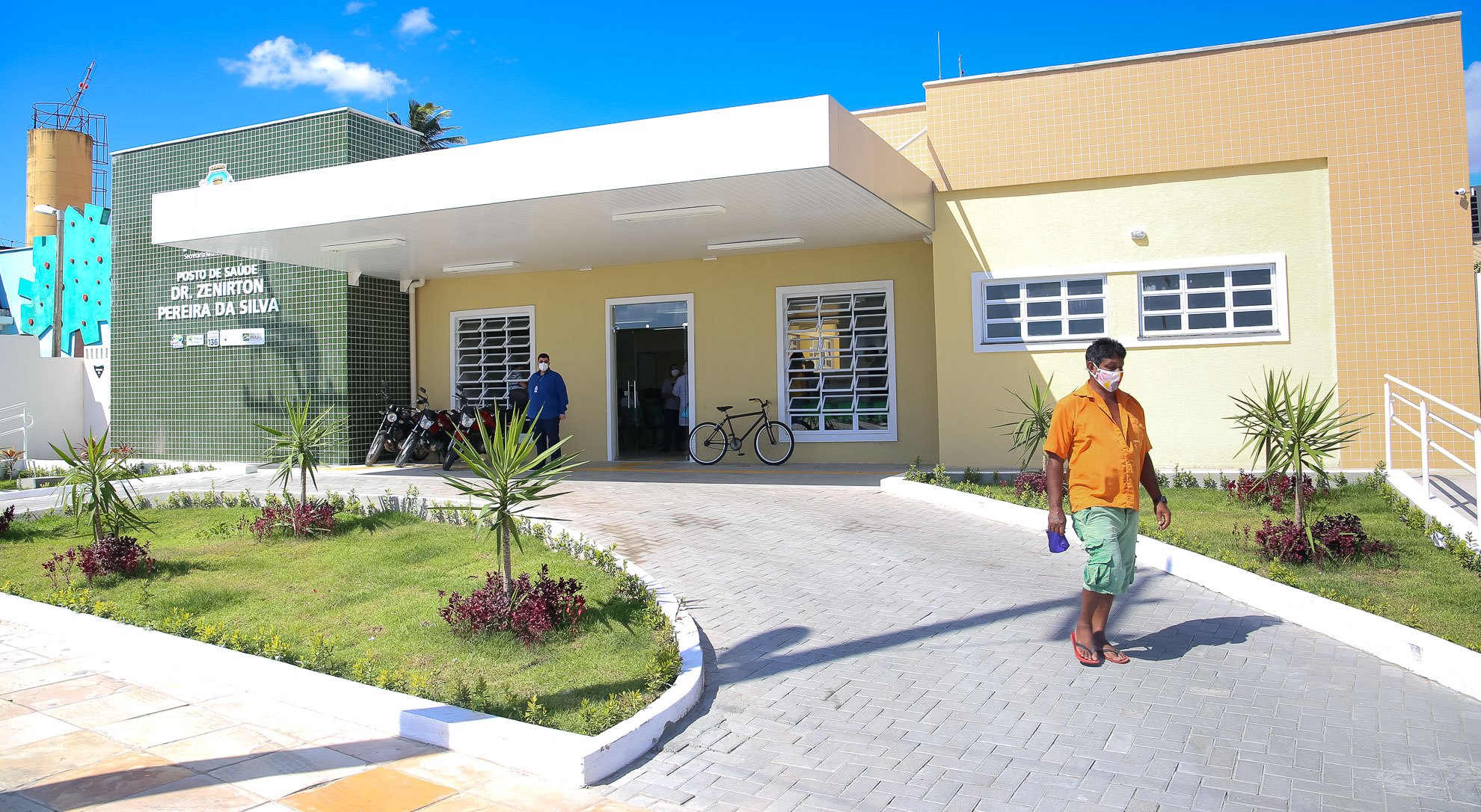 fachada do posto com senhor de máscara descendo a rampa de acesso